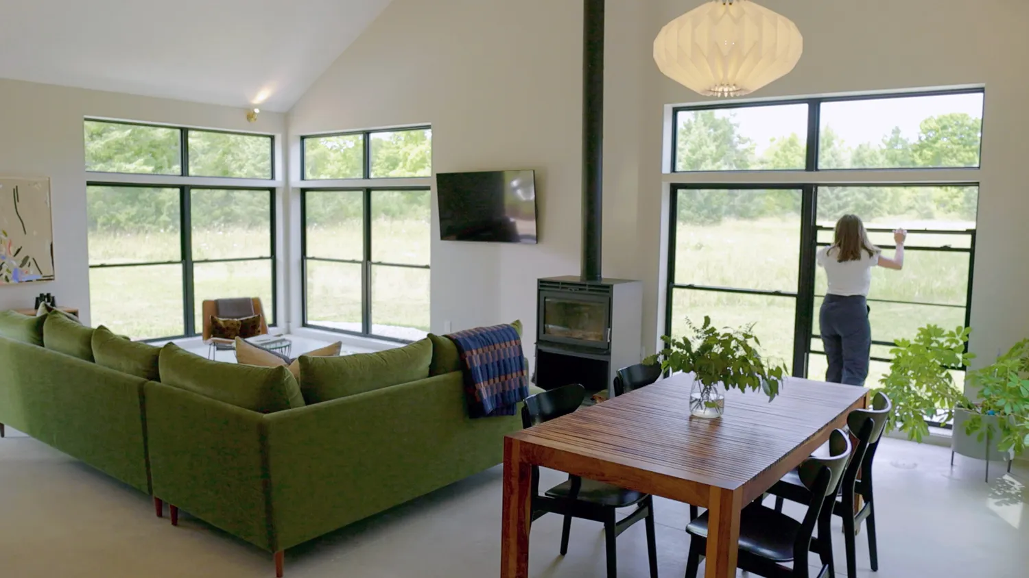 A bright living room with tall black-framed windows looking out on a field
