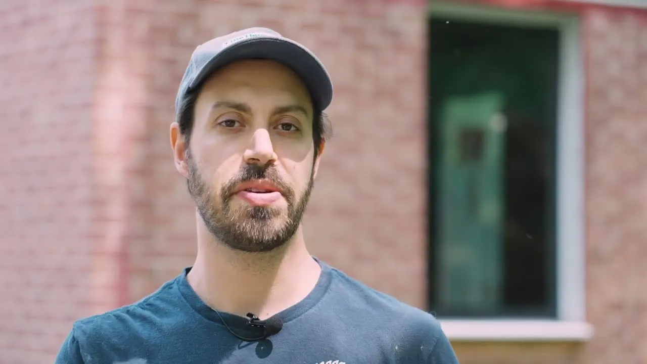 Builder Jon Beer talking in front of a new window set in a brick wall