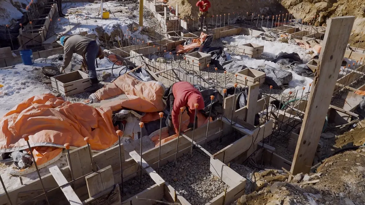 A crew setting rebar in the footing forms, with snow on the ground